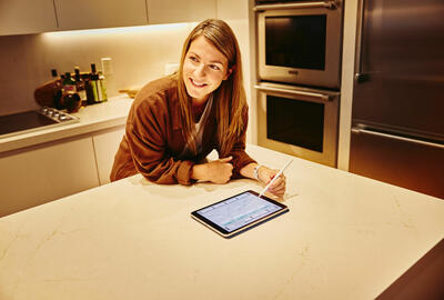 an image of a woman writing something on her tablet while looking to the left smiling