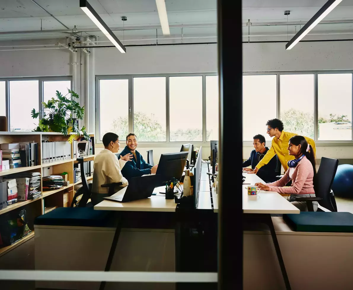 People working at an office setting, sitting behind a computer