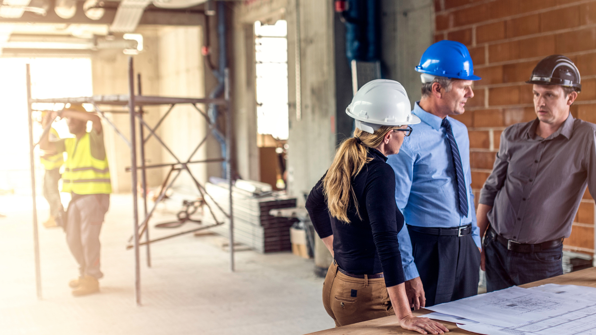 A photo of a woman and two men working in the construction sector