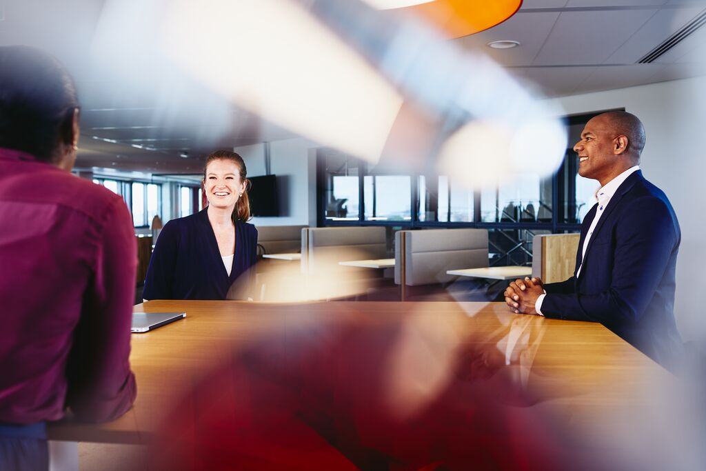 three people talking in a meeting room