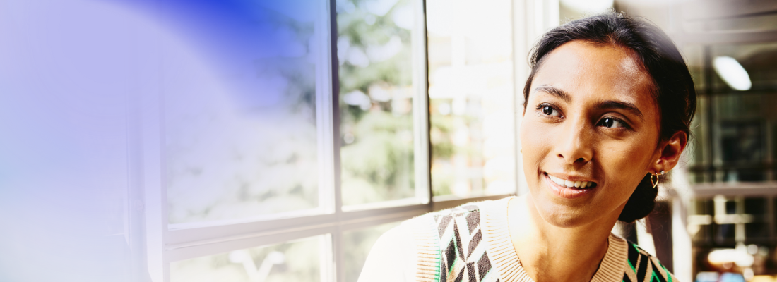 A woman smiling while seated on a windowsill