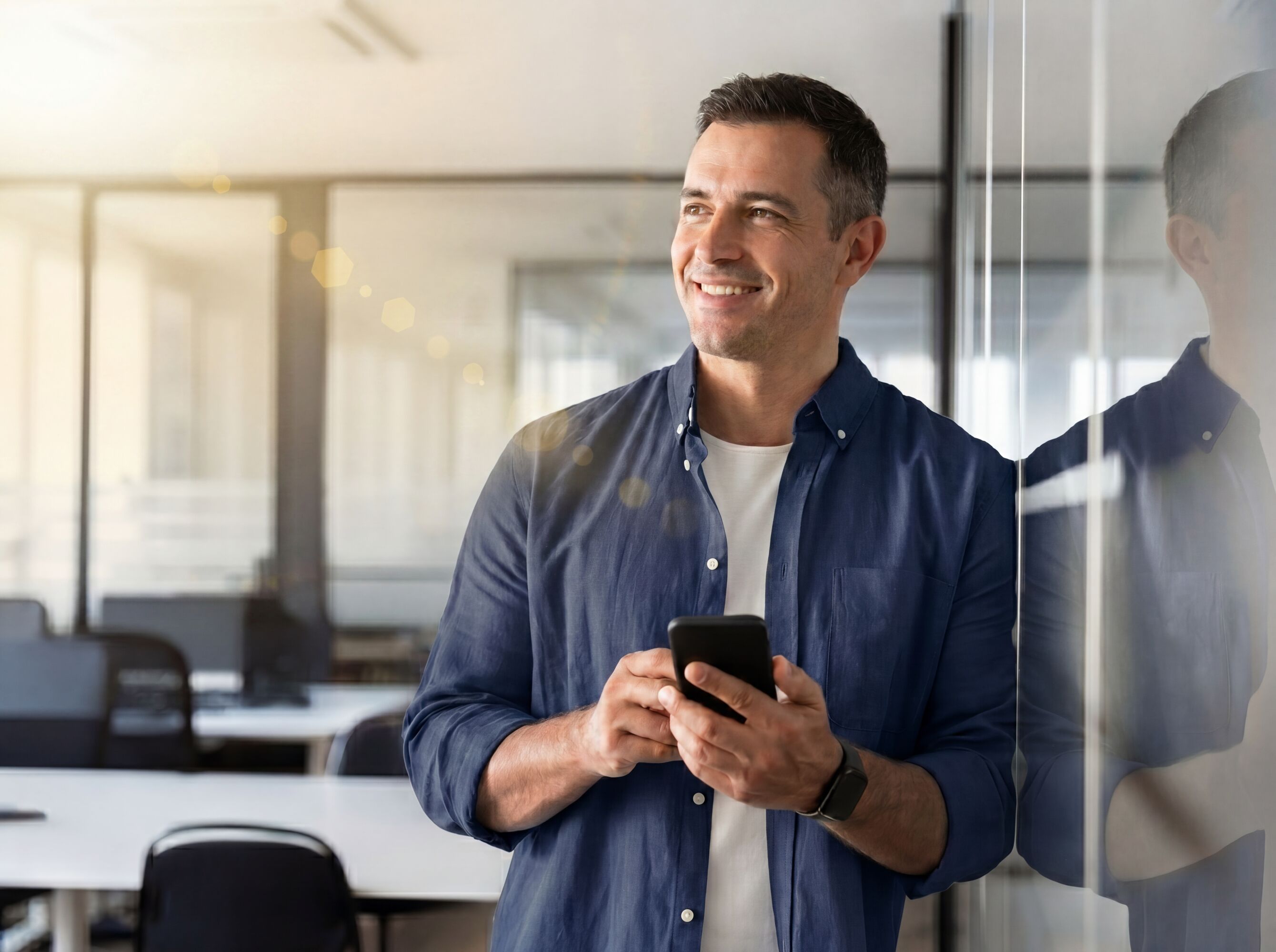 man standing in an office with a mobile phone in his hand