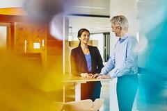 a man smiling at his female coworker while chatting