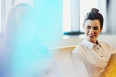 a woman talking to her coworker while smiling 