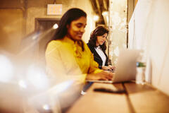 an image of a woman typing in her laptop while smiling