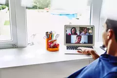 male working from home on laptop, meeting with colleagues in a video call.
