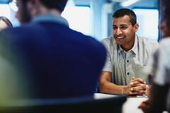 an image of a man in a meeting smiling at his coworkers