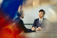 two men talking inside a meeting room