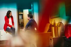 a man and woman talking and smiling while working