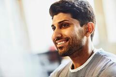 a bearded man looking to the left smiling