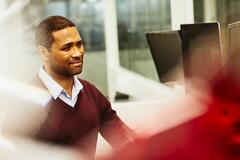 a man looking at his monitor while wearing a marron shirt