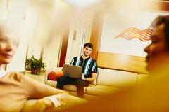 an image of a man smiling at his coworkers while typing at his laptop