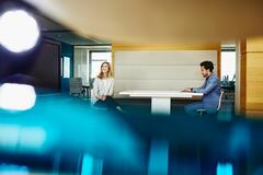 an image of two coworkers seated on a table smiling 