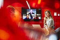 people in a meeting with others joining virtually