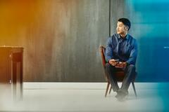 an image of a man seated on a chair while holding his phone