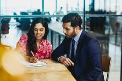 a woman writing something while discussing something to her coworker
