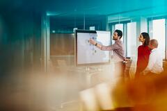 an image of a person presenting something to his team