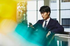 a man wearing a suit and glasses looking at his phone while seated
