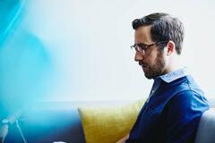 a bearded man wearing glasses reading something