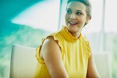 a woman wearing a sleeveless yellow top smiling