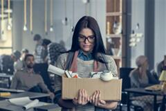 a woman wearing glasses carrying a box loaded with office supplies