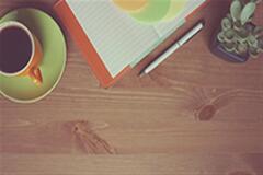 an image of a desk with a cup of coffee and a notebook and pen