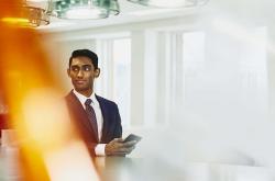 a man wearing a suit and tie holding a phone while looking to the left