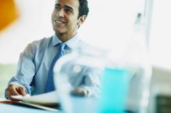 an image of a man wearing a light collared shirt and tie showing something to his coworker