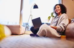 A woman sitting in the living room with her laptop