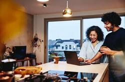 two people looking at a laptop conversing and smiling