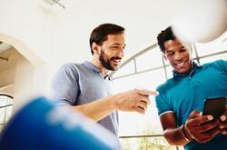 Two men smiling while looking at a phone