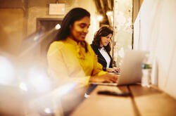 an image of a woman typing in her laptop while smiling