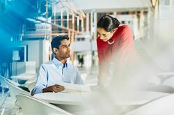 a man showing his female coworker something on a piece of paper