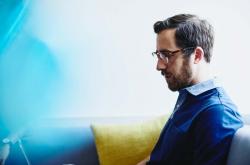 a bearded man wearing glasses reading something