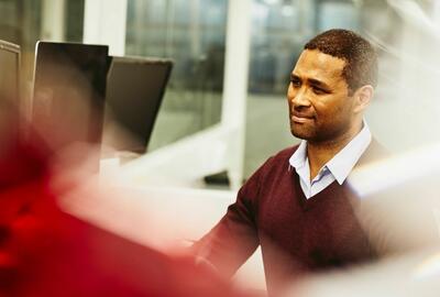 a man looking at his monitor while wearing a marron shirt