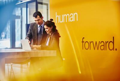 Man and woman looking at a laptop wearing suits