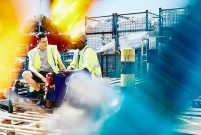two men where for construction sitting down and chatting while wearing reflective vests