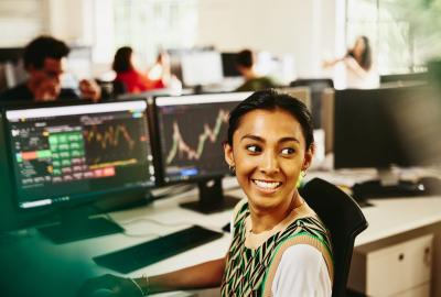 a woman smiling sitting at her desk whilst doing her work