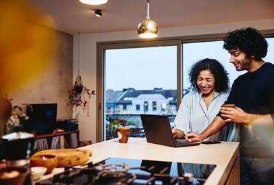 two people looking at a laptop conversing and smiling