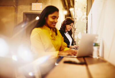 an image of a woman typing in her laptop while smiling