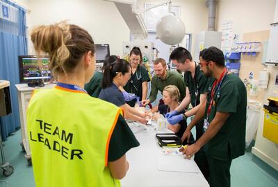 A medical team in a hospital doing a training session. They are being observed by a team leader.