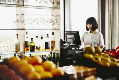 Woman standing behind a cash register.