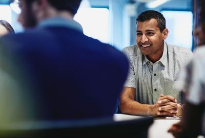 an image of a man in a meeting smiling at his coworkers