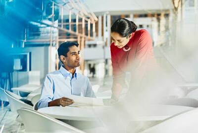 a man showing his female coworker something on a piece of paper