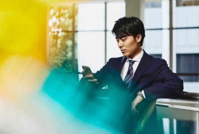 a man wearing a suit and glasses looking at his phone while seated