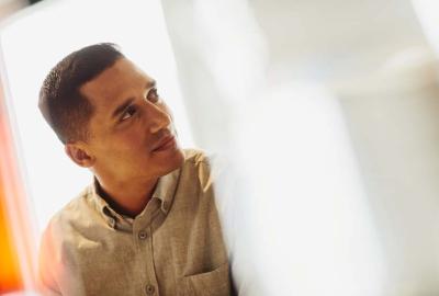 a man wearing a light coloured collared shirt looking to the right