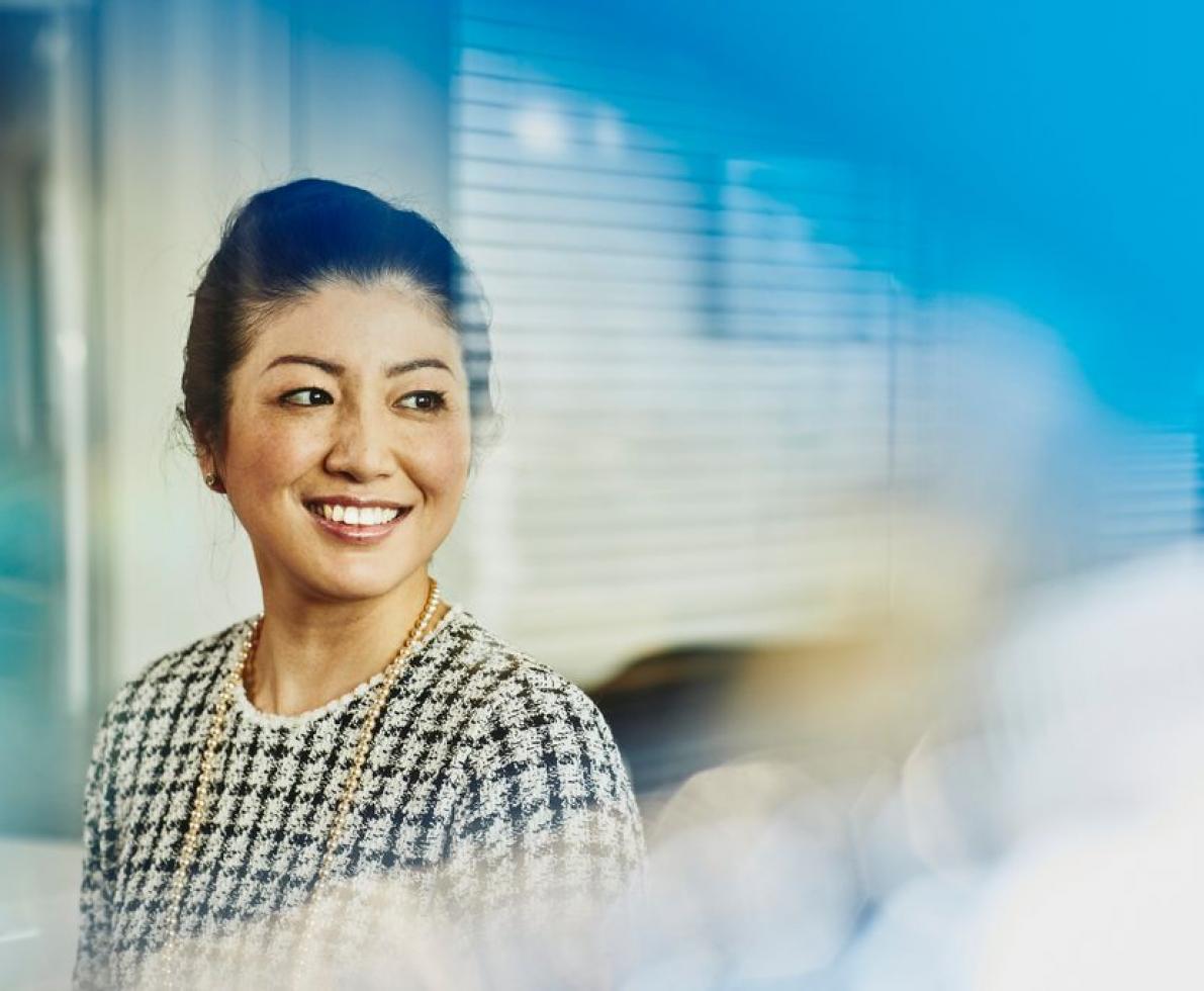 an image of a woman with her hair in a bun smiling while looking to the right