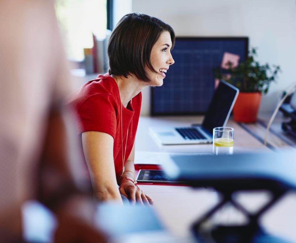 a woman wearing a red shirt chatting with her colleague 