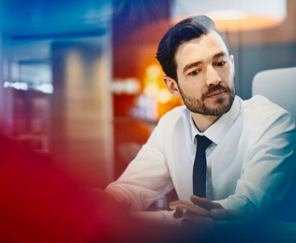 a man wearing a white button up shirt and tie looking at his coworker's work
