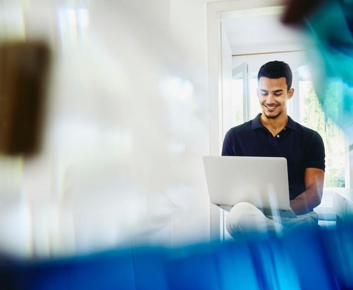 a man working on something in his laptop smling a man working on something in his laptop smling